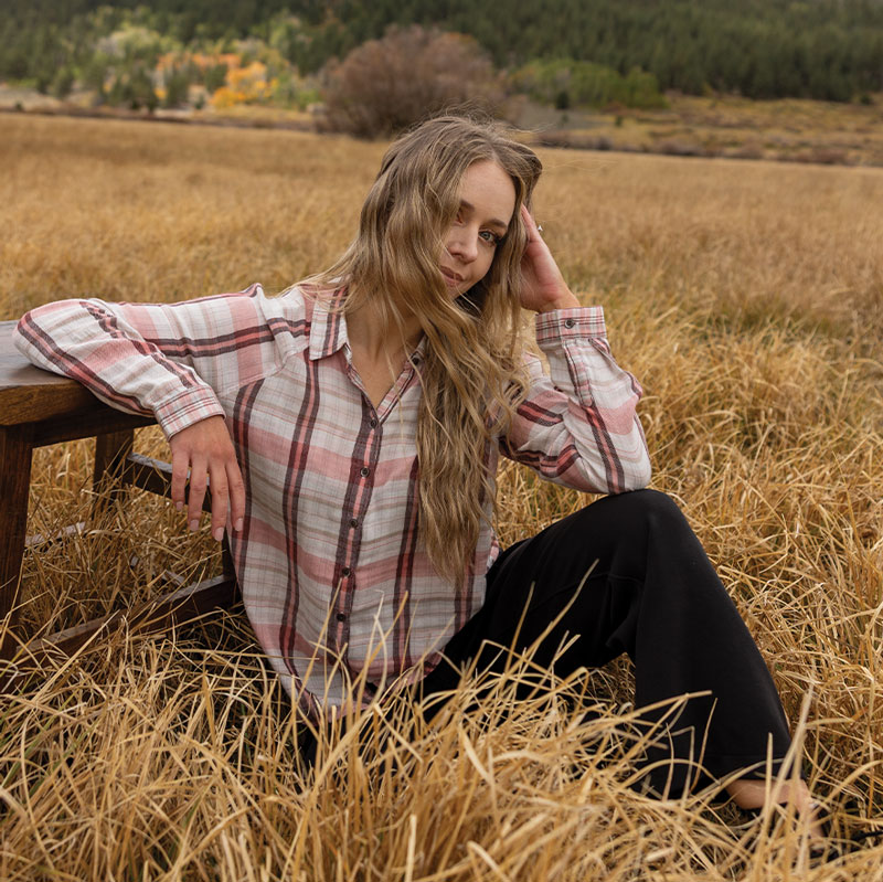 Woman sitting in field of tall grass during fall.