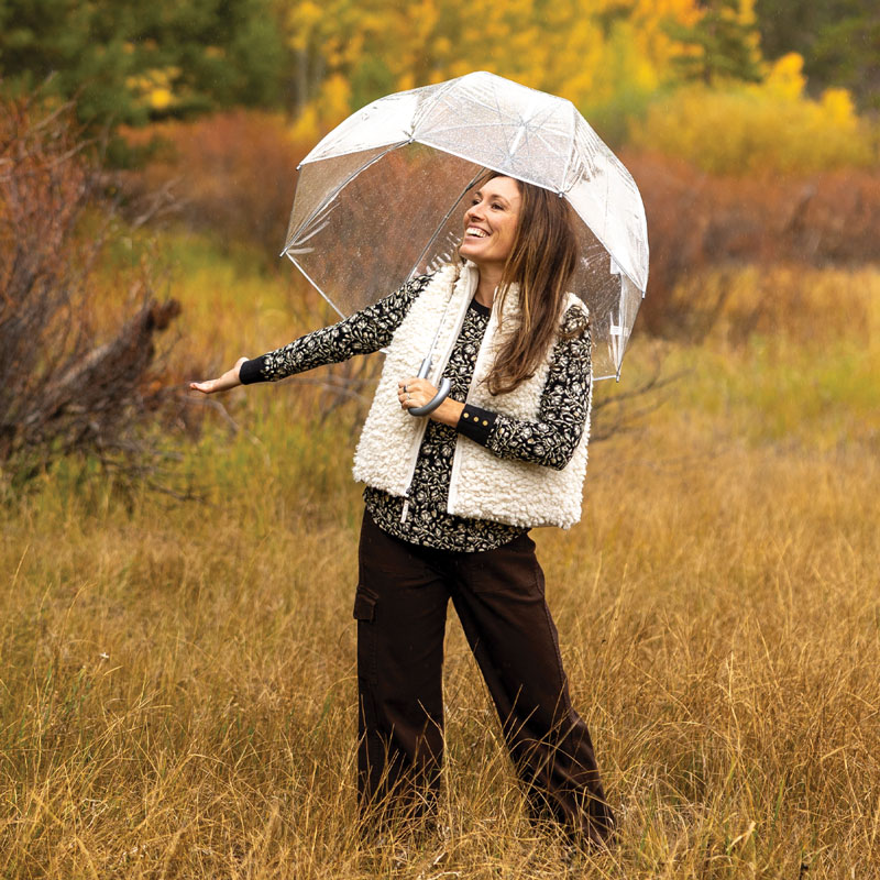 Woman in field during fall with light rain coming down.